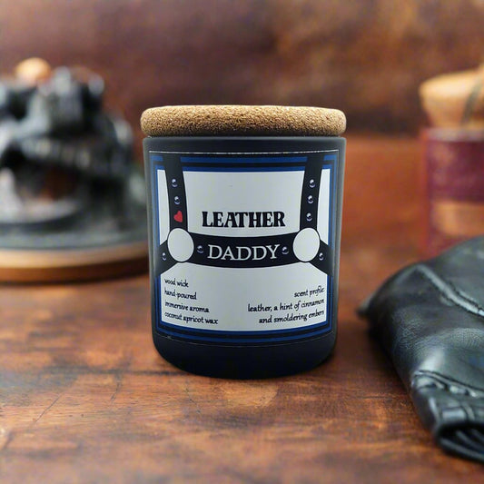 Bold 'Leather Daddy' candle in a sleek matte black glass jar with a cork lid, exuding an intense scent profile of rich leather, warm cinnamon, and smoky smoldering embers. The design and aroma evoke strength and warmth, offering a sensory experience of rugged sophistication